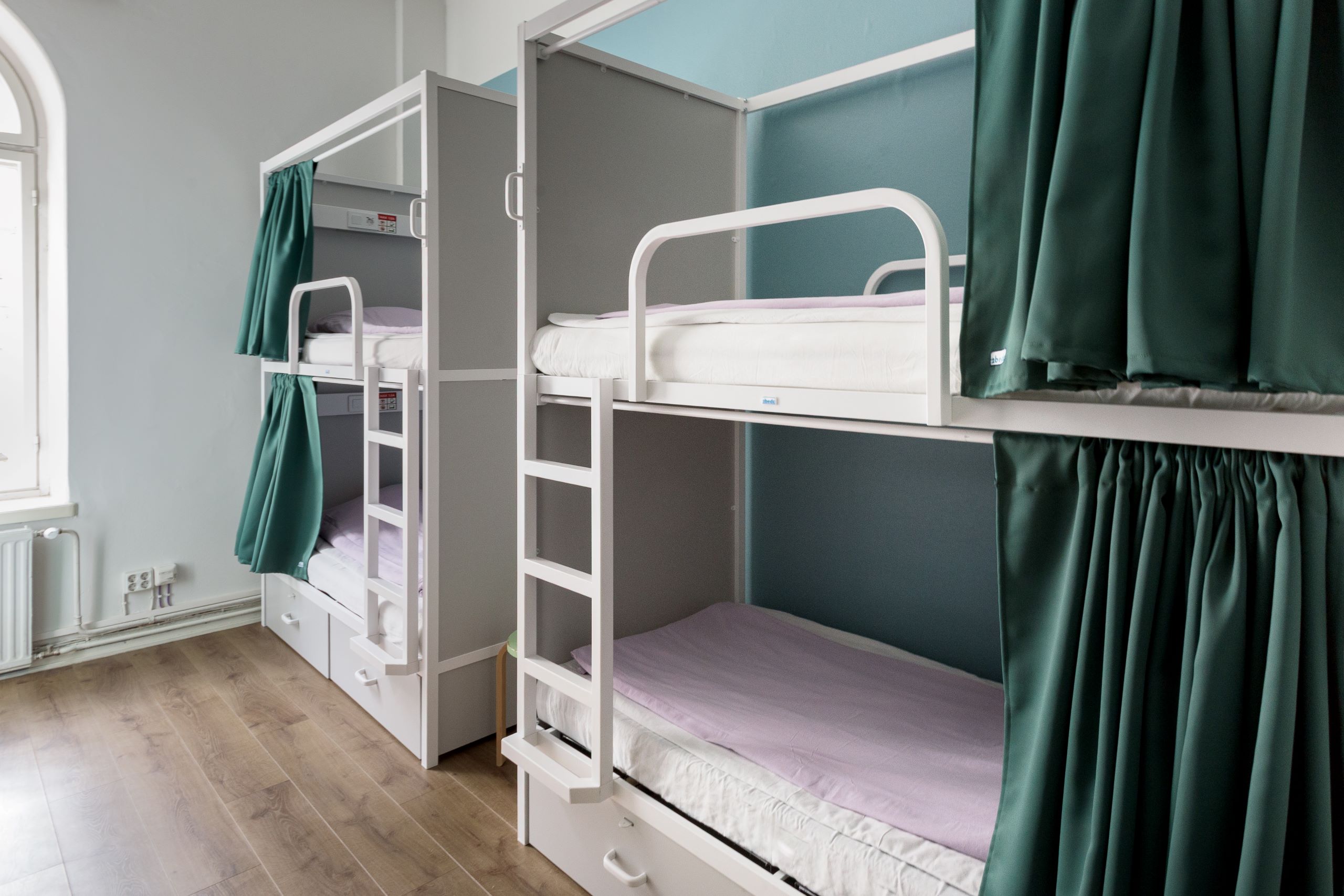 Spacious 8-bed mixed dorm with bunk bed privacy curtains and reading lights in central Helsinki